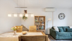 A modern living room with a wooden dining table, a green sofa, and a wall-mounted clock. - Apartment “Linie 8” with Wi-Fi (Dresden)