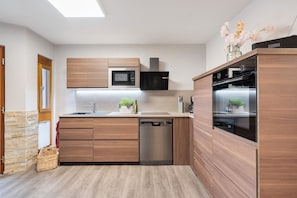 Eine moderne Küche mit Holzausstattung, eingebautem Mikrowellenherd, Backofen und Geschirrspüler.