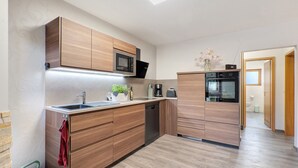 A modern kitchen with wooden cabinets, a built-in microwave, and a dishwasher. - Apartment “Linie 8” with Wi-Fi (Dresden)
