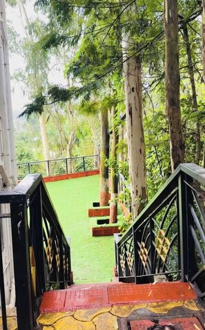 Escadaria que leva a uma área verde com árvores e guarda-corpo.