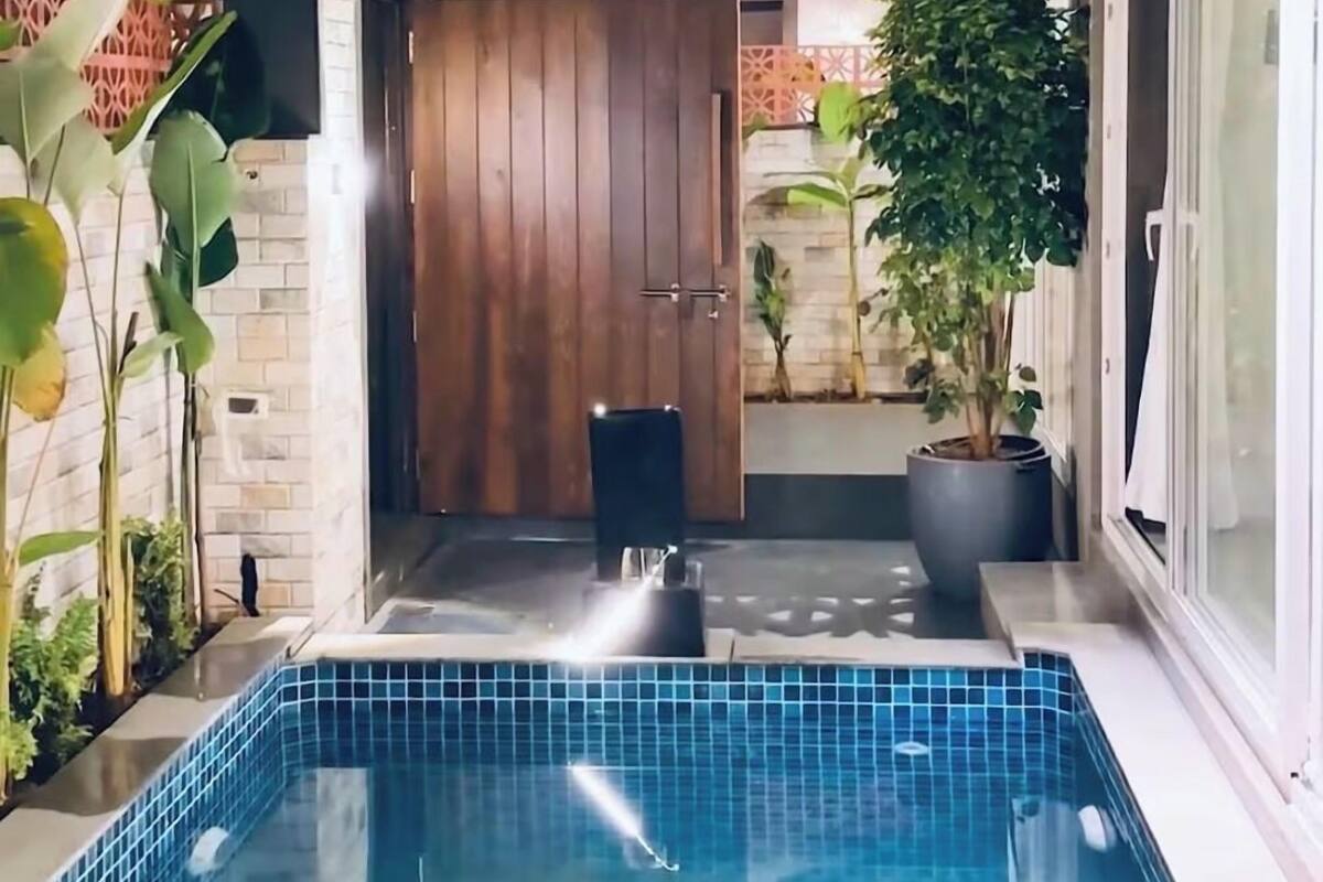 Et moderne poolområde udend ørs med en trædør, plantekasser og en flisebelagt pool.