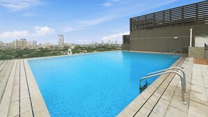 A rooftop swimming pool with a cityscape view, metal railings, and a modern building structure. - Bloomfields Modern 1BR in Azizi Vista (Dubai)