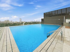 A rooftop swimming pool with a cityscape view, metal railings, and a modern building structure. - Bloomfields Modern 1BR in Azizi Vista (Dubai)