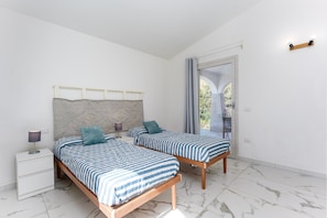 Une chambre avec deux lits, une table de chevet, une lampe et une vue sur l’extérieur.