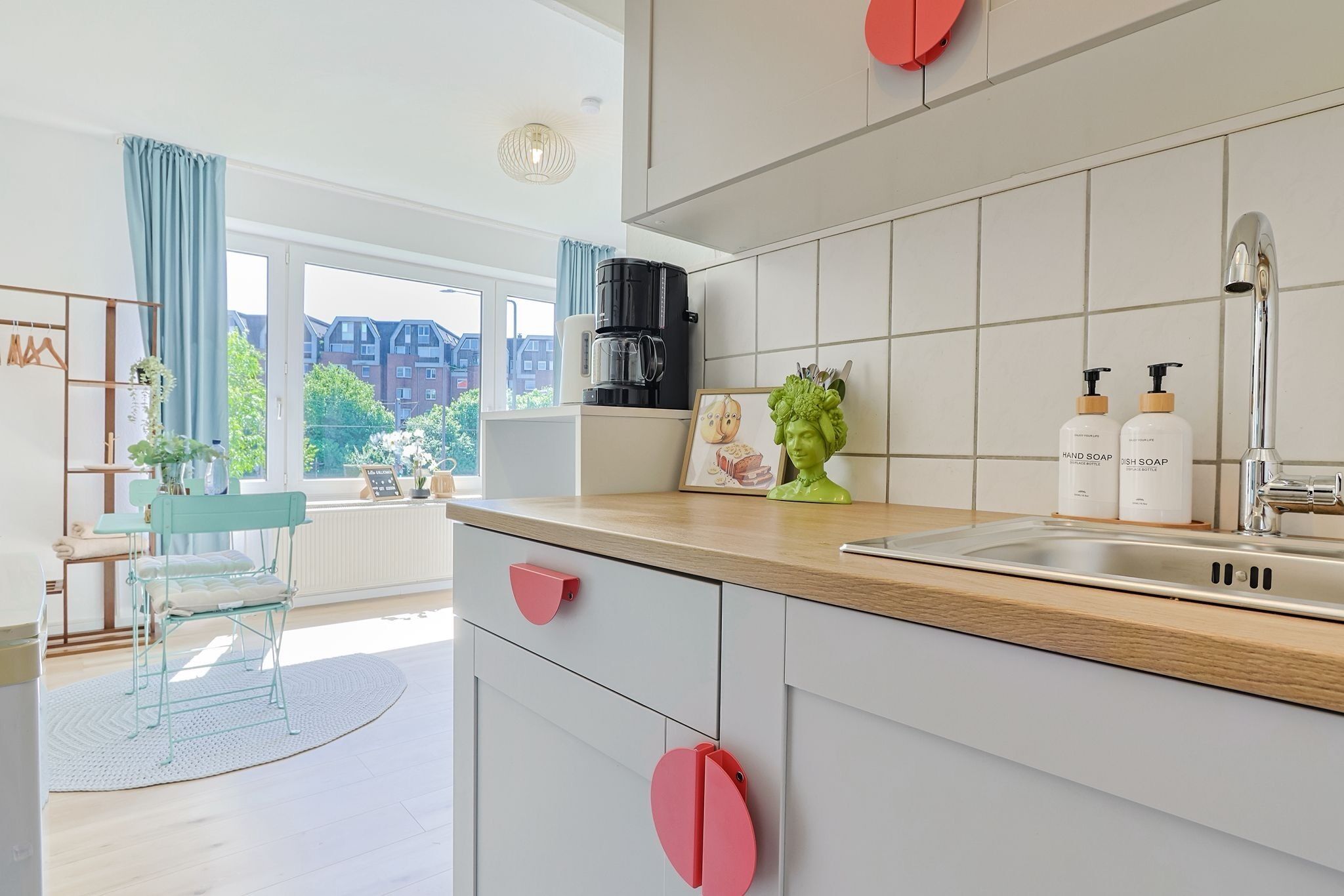 Een moderne keuken met een groot raam, een koffiezetapparaat en een spoelbak.