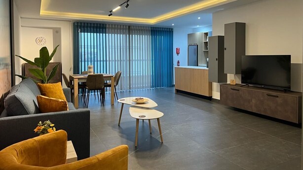 A modern living room with a sofa, coffee table, and TV. - Luzzu Harbour Suites Modern 2BR in Marsaxlokk (Marsaxlokk)