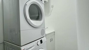 A laundry room with stacked washing machines and a dryer. - Luzzu Harbour Suites Modern 2BR in Marsaxlokk (Marsaxlokk)