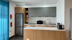 A modern kitchen with a built-in refrigerator, microwave, and sink. - Luzzu Harbour Suites Modern 2BR in Marsaxlokk (Marsaxlokk)