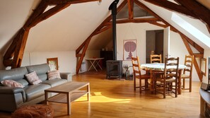 A loft-style room with a sofa, wooden dining table, and chairs. - Holiday Home Haras de la Fontaine Droopy (Poligny)