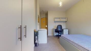 Een compacte, praktische slaapkamer met een bed, bureau, stoel en kledingkast.