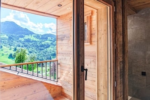 A wooden interior with a balcony overlooking a mountainous landscape.