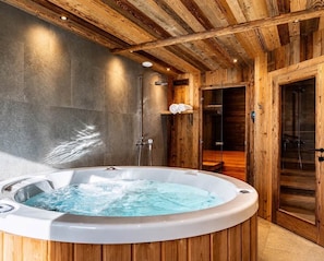 A wooden cabin interior with a hot tub, a shower, and a sauna.