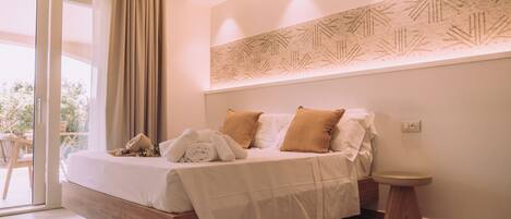 A modern bedroom with a bed, bedside table, and a view through a glass door.