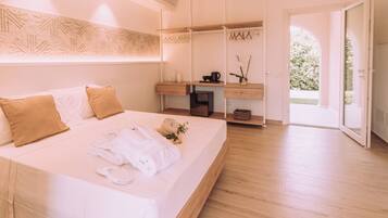 Un dormitorio moderno con una cama grande, un escritorio de madera y vistas a un jardín desde una puerta abierta.