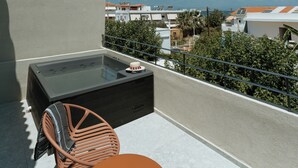 Eine Dachterrasse mit Whirlpool, Tisch und Stühlen.