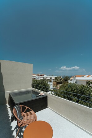 Terraza en la azotea con jacuzzi, mesa y sillas.