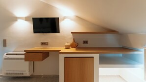 Ein moderner, minimalistischer Raum mit Schreibtisch, Wand-Fernseher und Klimaanlage.