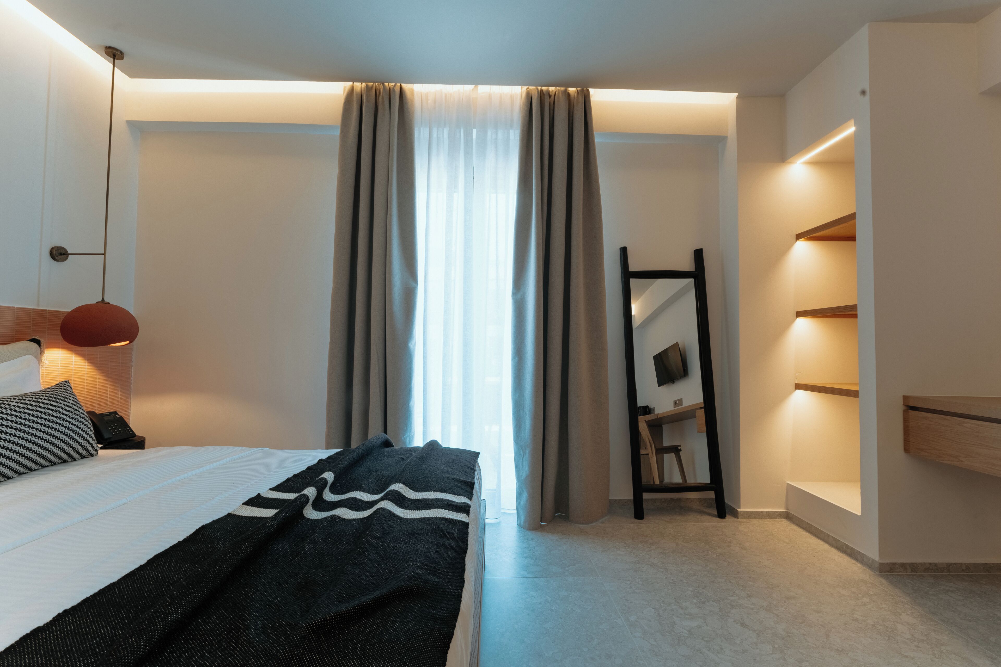 Une chambre à coucher moderne avec un lit, une lampe de chevet, un miroir et une armoire.