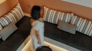 Ein modernes Wohnzimmer mit einer Eckcouch, einem runden schwarzen Tisch und einem hellen Boden.