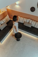 Una sala de estar moderna con un sofá modular, una mesa redonda negra y suelo de tonos claros.