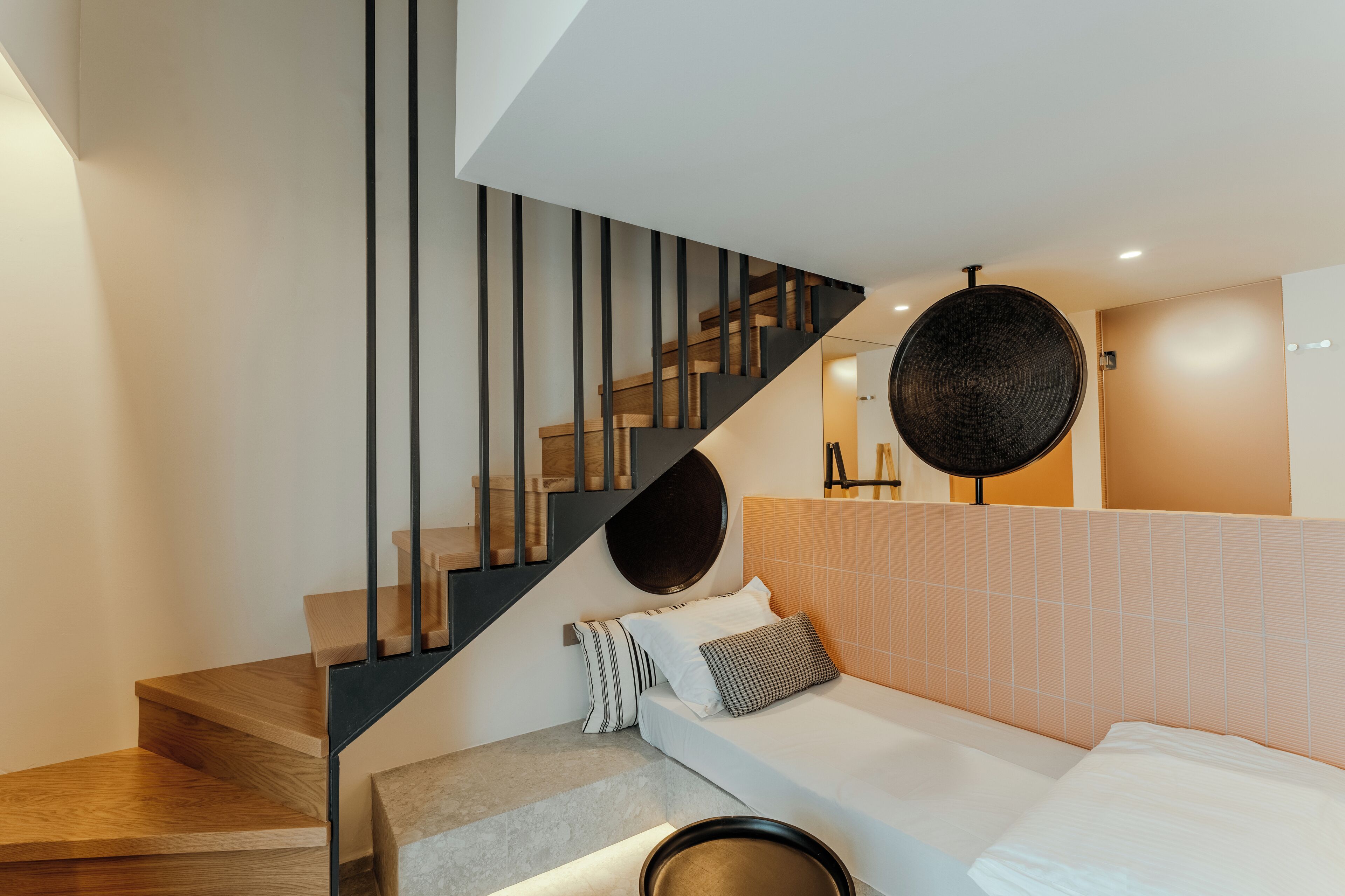 Un interno moderno con una scala, un letto e un oggetto circolare fissato al muro.