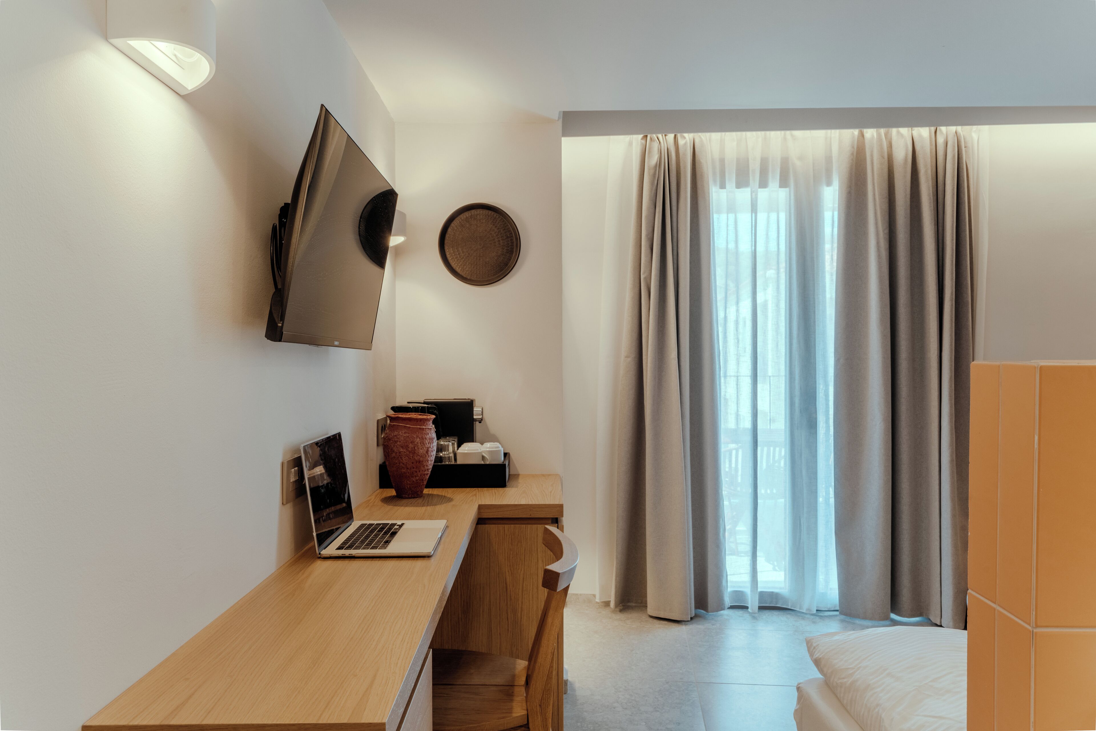 Ein modernes Schlafzimmer mit einem Holztisch, einem Laptop, einer Vase und einem Bett.
