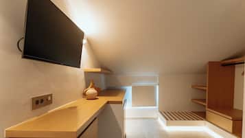 Eine moderne Küche mit Holzarbeitsplatten, einem eingebauten Backofen und einem an der Wand montierten Flachbildfernseher.