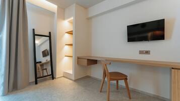 Een moderne kamer met een bureau, stoel, televisie en inbouwplanken.