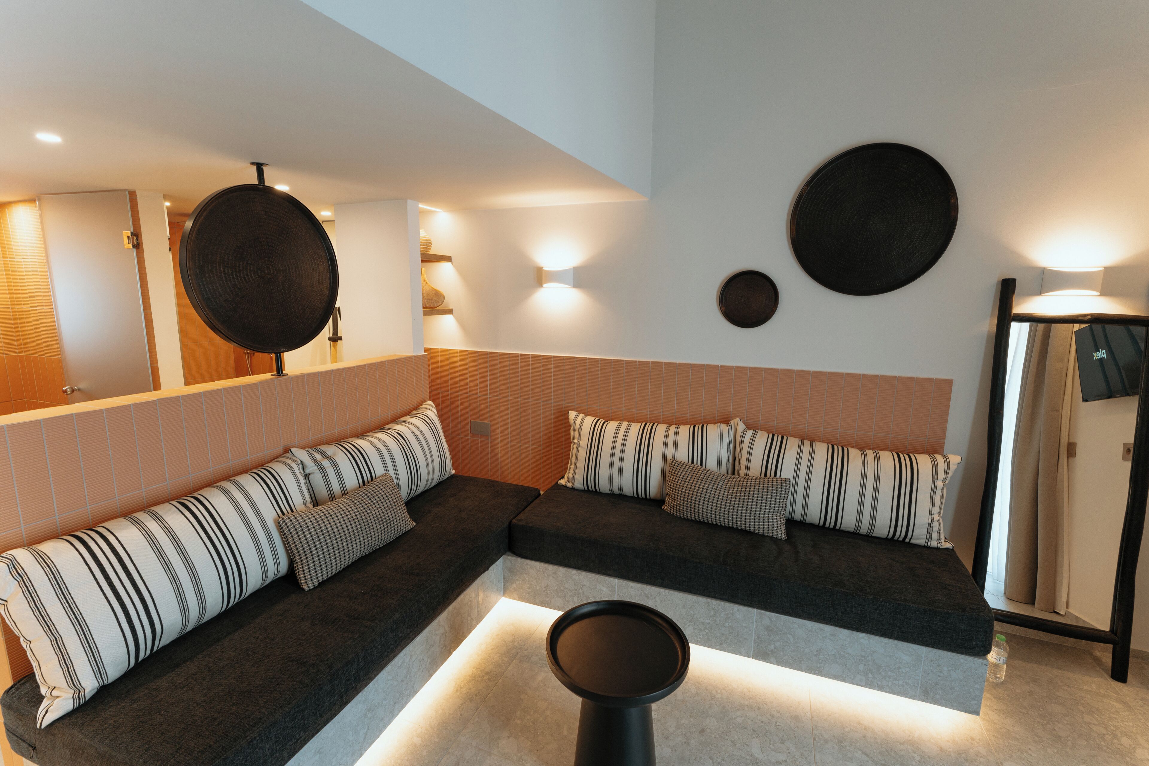 Een moderne woonkamer met een modulaire bank, een ronde salontafel en wandlampen.