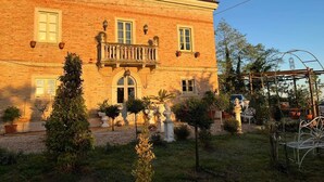 Un edificio de ladrillo con balcón, plantas en macetas y un jardín.