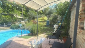 Un patio cubierto con piscina, sillas de exterior y una mesa decorativa.