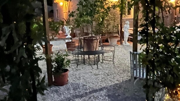 Un patio al aire libre con piso de grava, plantas en macetas y un conjunto de asientos.