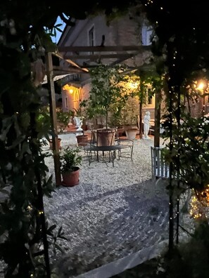 Un'area patio esterna con pavimento in ghiaia, piante in vaso e un angolo salotto.