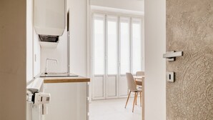 A modern kitchen with a built-in oven, a microwave, and a water dispenser. There is a dining area with a table and chairs, and a large window with a view of the outside. - Hostmate - Milano - Viale Corsica (Milano)
