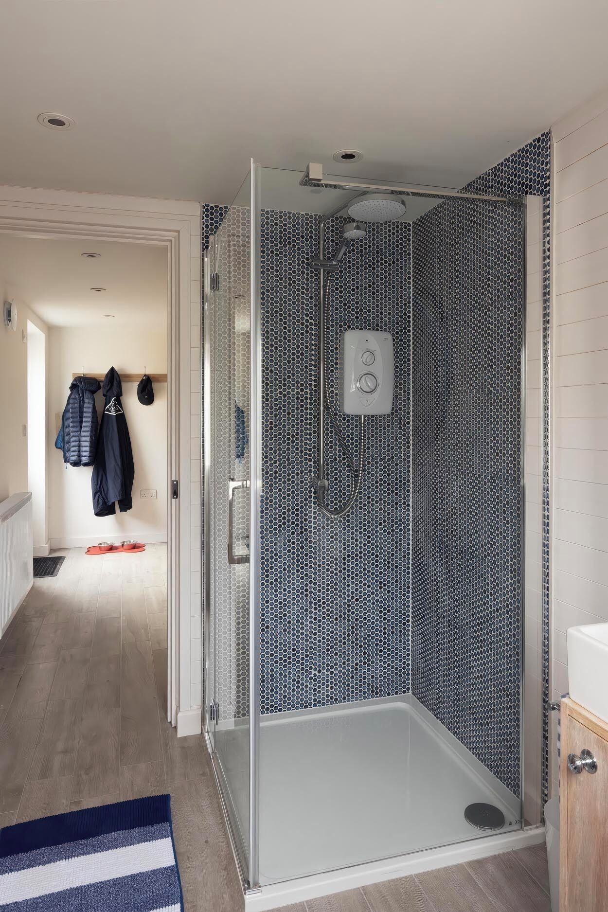 Un baño moderno con cabina de ducha de vidrio, lavamanos blanco y pared con estampado.