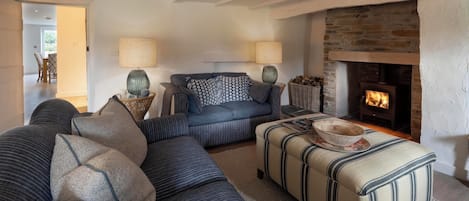 A cozy living room with a sofa, ottoman, and a fireplace.