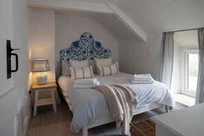 A bedroom with a bed, bedside lamp, and a window with curtains.