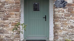 A green door with a small window above it, set in a stone wall with a stone plaque above the door. - Rose Cottage (Wadebridge)