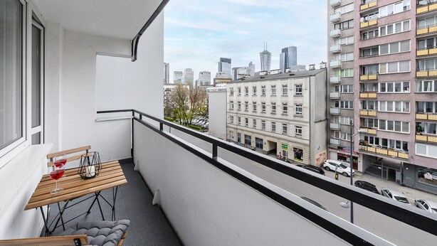 En balkon med et bord, stole og udsigt over bybilledet.