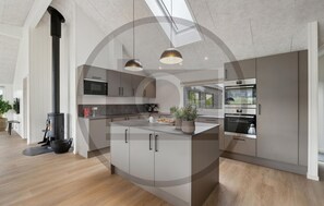 A modern kitchen with a central island, built-in appliances, and pendant lighting. - Amazing home in Bogense with sauna (Bogense)
