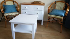 A room with two wicker chairs, a white table, and a white dresser with drawers. - Studio near the Dordogne river, close to all amenities. Pastoral setting, (Argentat-sur-Dordogne)