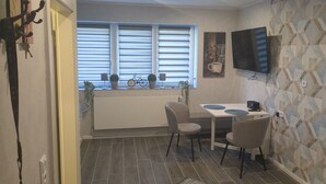Une cuisine de taille réduite comprenant un coin repas, un radiateur et un téléviseur fixé au mur.