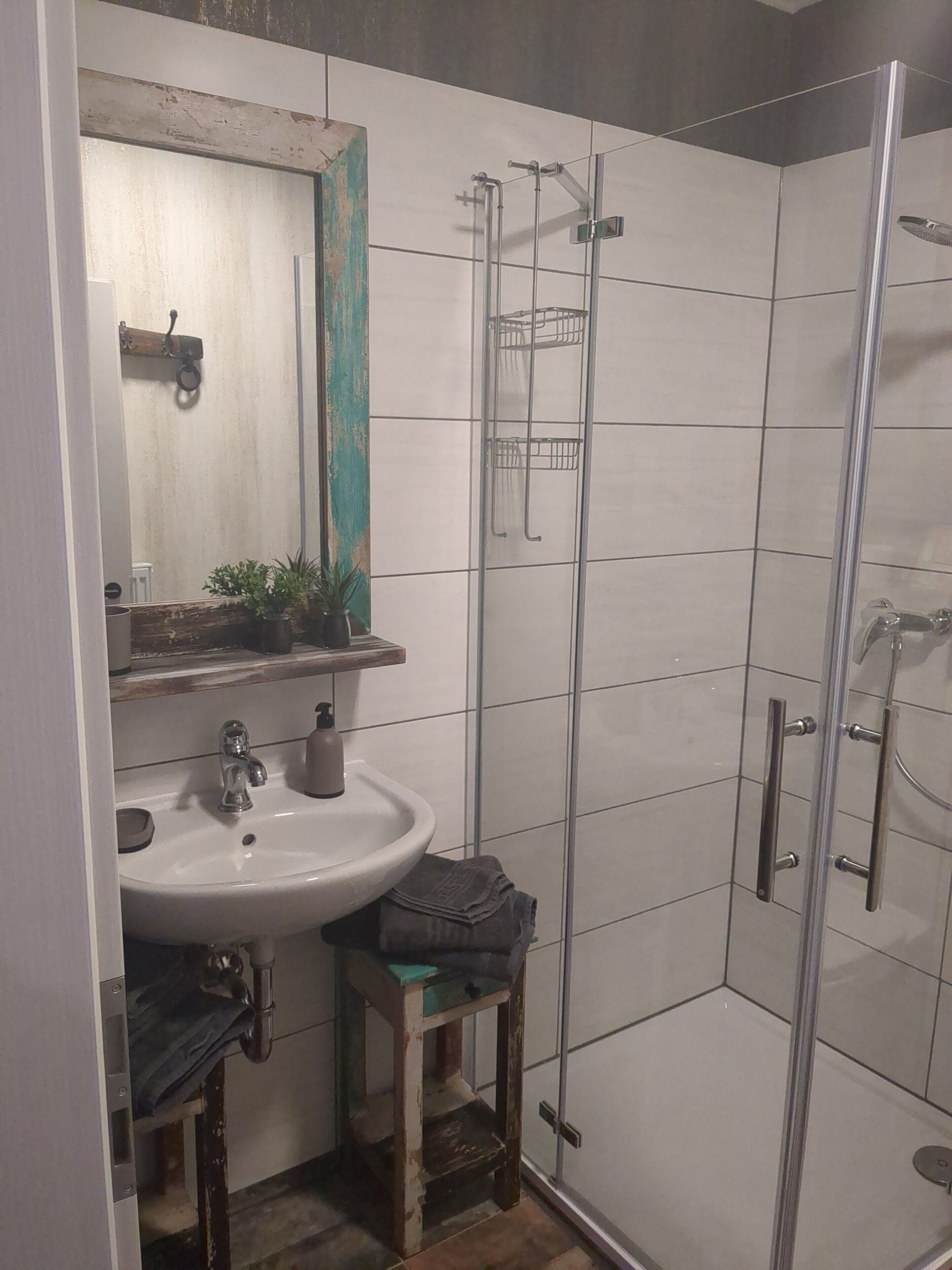 A bathroom with a sink, mirror, towel rack, and a glass-enclosed shower area.