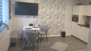 Une cuisine moderne dotée d’un téléviseur à écran plat, d’une table à manger avec des chaises et d’un crédence décorée.