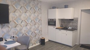 Une cuisine compacte avec des meubles blancs, un four encastré et un crédence décorée.