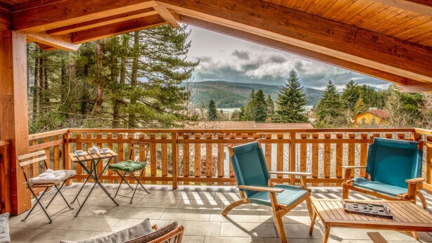 A wooden deck with outdoor furniture, a table with cups and a teapot, and a view of trees and mountains. - Sky Room - Casa Silva (Lorica)