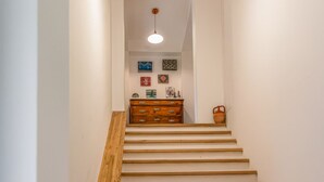 A staircase with wooden steps and a wooden handrail, leading to a room with a dresser and wall art. - Sky Room - Casa Silva (Lorica)