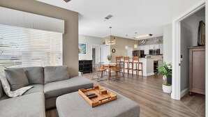 Uma sala de estar moderna com um sofá seccional, uma mesa de centro de madeira e uma área de jantar com mesa e cadeiras.