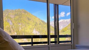 Un dormitorio con cama, almohada y vistas a un paisaje montañoso a través de una puerta corredera.