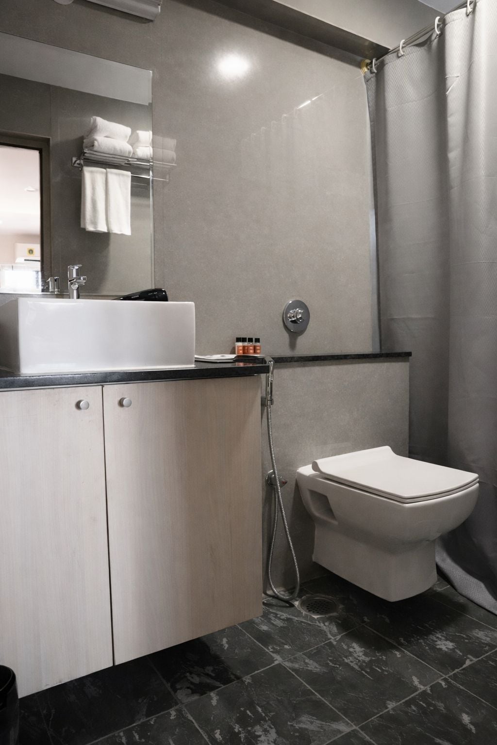 A modern bathroom with a white sink, mirror, and toilet.